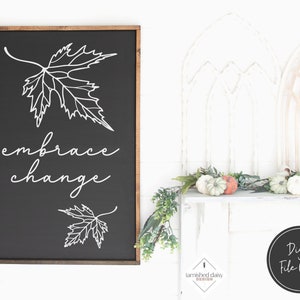 May include: Black and white digital download of a sign with the text "embrace change" and a stylised maple leaf design. The sign is framed in a dark wood frame.