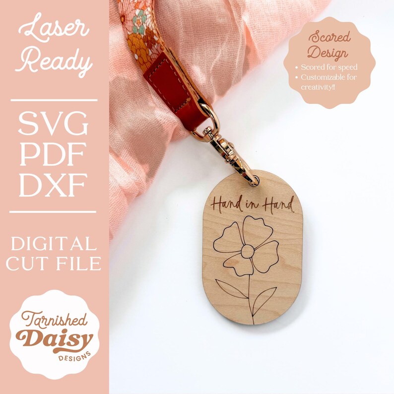 Puede incluir: Un llavero de madera con un dise&ntilde;o de flor y el texto "Mano a mano" grabado en &eacute;l. El llavero est&aacute; unido a un anillo de metal dorado.