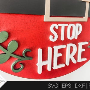 May include: Red and green wooden sign with the words "STOP HERE" in white raised letters. The sign is decorated with green leaves.