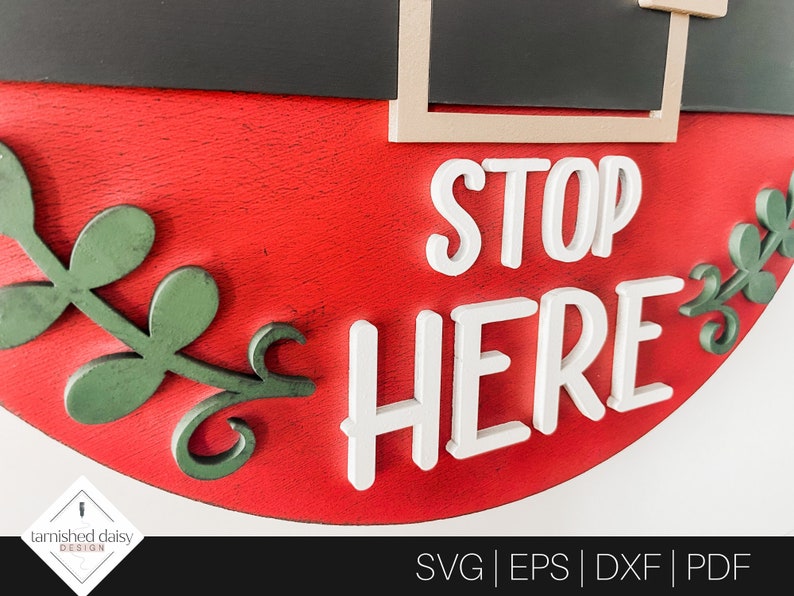 May include: Red and green wooden sign with the words "STOP HERE" in white raised letters. The sign is decorated with green leaves.
