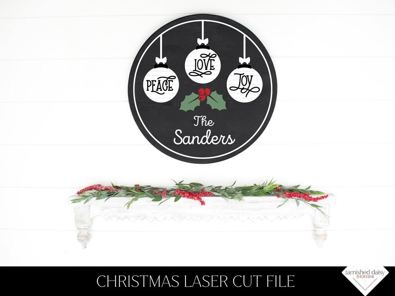 May include: Black circular sign with three white ornaments that say "Peace", "Love", and "Joy".  The sign also has a green holly sprig with red berries and the text "The Sanders".