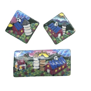 Puede incluir: Un conjunto de tres pendientes de cerámica que representan una escena de granja colorida y caprichosa con graneros rojos, un silo y un cielo azul. Los pendientes tienen forma de rectángulo y dos diamantes.