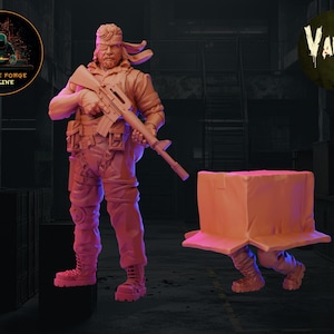 May include: A painted miniature figurine of a soldier wearing a bandana and holding a rifle. The soldier is standing next to a painted miniature box with legs.
