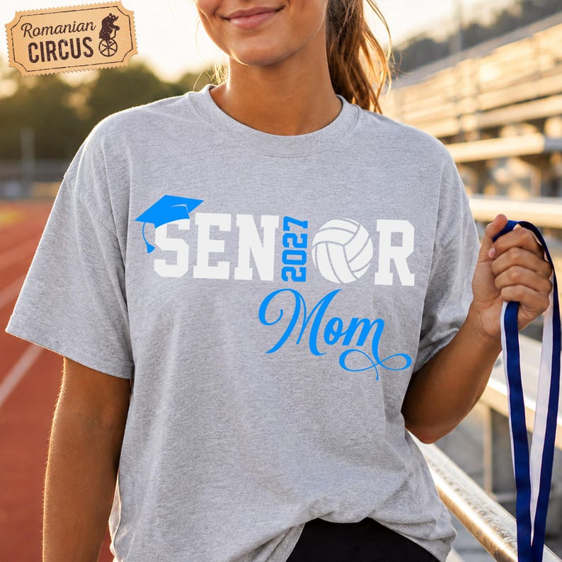 Pu&ograve; includere: Una t-shirt grigio m&eacute;lange a maniche corte con la scritta SENIOR MOM in bianco e blu. La lettera I &egrave; sostituita da un tocco di laurea blu e la lettera O da una pallavolo bianca. L'anno 2027 &egrave; stampato in blu.