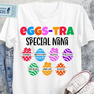 May include: White t-shirt with the text "EGGS-TRA SPECIAL NANA" in colorful letters. Below the text are Easter egg designs with names: Sophia, Benjamin, Olivia, William, Michael, Abigail, and Mason. A pair of white sneakers and jeans are in the image.