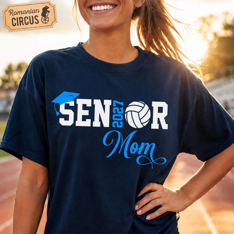 Pu&ograve; includere: Una t-shirt blu navy con la scritta bianca SENIOR, un tocco di laurea blu sopra la prima lettera e una pallavolo bianca che sostituisce la lettera O. L'anno 2027 &egrave; stampato in blu verticalmente e la parola Mom in corsivo blu.