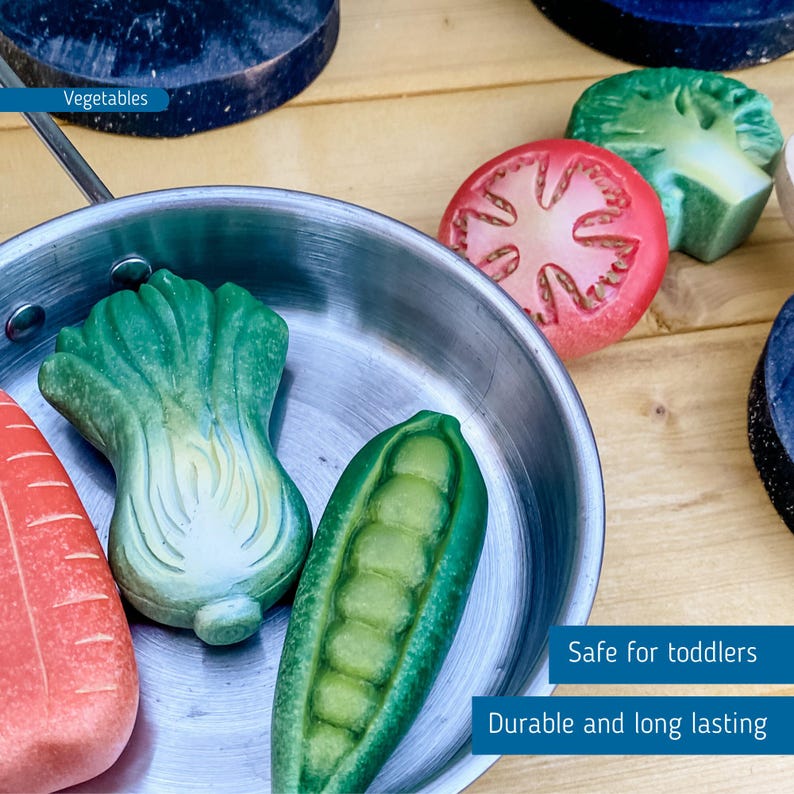 May include: A silver toy pan filled with wooden toy vegetables, including a green pea pod, a green lettuce, and a red carrot. The text "Vegetables" is visible in the top left corner of the image. The text "Safe for toddlers" and "Durable and long lasting" is visible in the bottom right corner of the image.