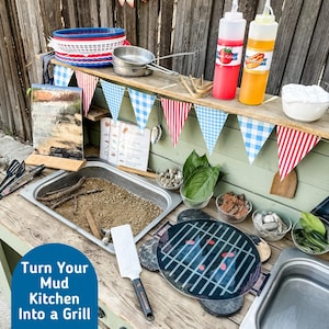 Könnte beinhalten: Eine Outdoor-Spielküche für Kinder mit einem Holztisch, einem Metallbecken und einem Spielzeuggrill. Der Tisch ist mit rot-weiß-blauen Wimpeln dekoriert und enthält Spielzeug-Lebensmittel, Gewürze und Kochutensilien. Der Text "Turn Your Mud Kitchen Into a Grill" ist sichtbar.