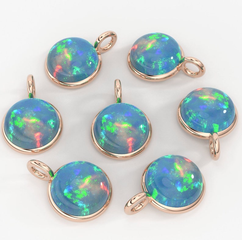 May include: Six round pendants featuring cabochon-cut blue opals with vibrant green and red flashes, each set in a polished rose gold-toned metal bezel with a small circular bail attached at the top for hanging on a chain or cord.