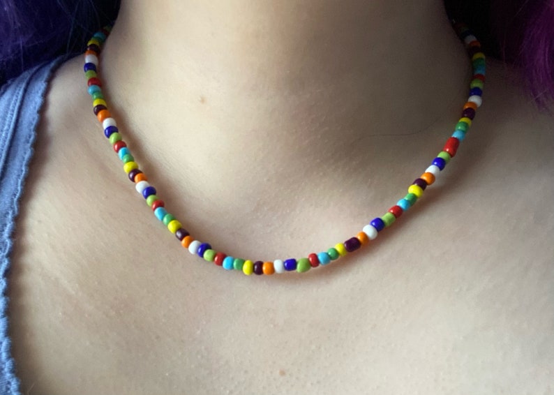May include: A colorful beaded necklace with alternating beads of red, orange, yellow, green, blue, purple, and white.