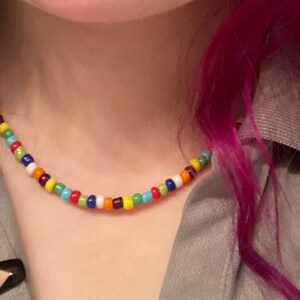 May include: A colorful beaded necklace with a variety of colors, including red, orange, yellow, green, blue, purple, and white.