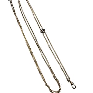 May include: A long gold-tone chain necklace featuring a series of interconnected oval links. The necklace includes a small, square-shaped central charm decorated with three tiny white circular accents arranged in a vertical row and a lobster claw clasp.