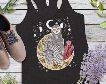 May include: A black tank top featuring a graphic of an owl perched on a crescent moon with floral accents. The owl is grey and white with yellow eyes. The moon is gold with a floral design. The background is black with white stars and a white crescent moon.