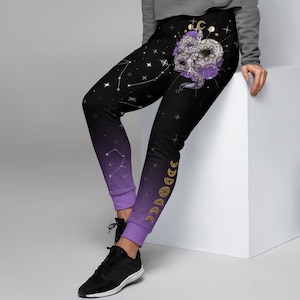 May include: Black and purple joggers with a celestial design. The joggers feature a gradient from black to purple, with constellations and moon phases. A white and purple snake design is on the upper leg.