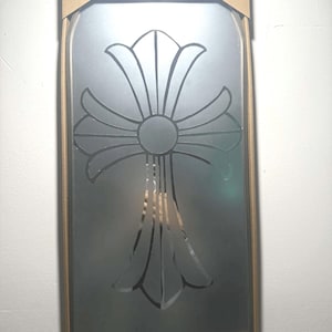 Op de afbeelding: Een boogvormige wandspiegel met een groot, geëtst kruisontwerp in het midden. De spiegel zit in een bruin kartonnen frame met de tekst Mirror CHROME HEARTS bovenaan en de afmetingen Ca. 30 x 70 cm onderaan afgedrukt.