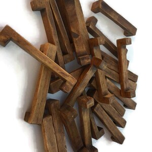 Op de afbeelding: Een stapel van 20 rustieke houten ladegrepen in een donkerbruine vlek. De grepen zijn allemaal even groot en in dezelfde vorm, met een eenvoudig rechthoekig ontwerp.