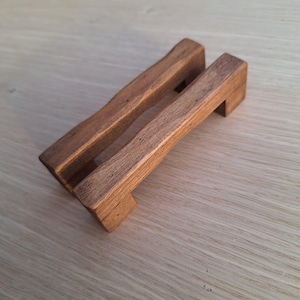 Può includere: Due tiretti per cassetti in legno con finitura rustica. I tiretti hanno la forma di una piccola panca con la parte superiore leggermente curva.