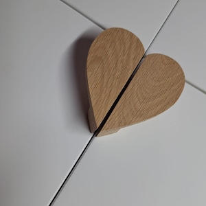 May include: A wooden heart-shaped door pull with a natural wood finish.