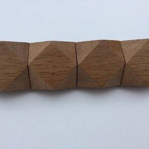以下が含まれることがあります： ダイヤモンド型の面を持つ木製の幾何学的な形が5つセットになっています。 形はつながっていて、長い長方形のピースを形成しています。 木材は薄い茶色です。