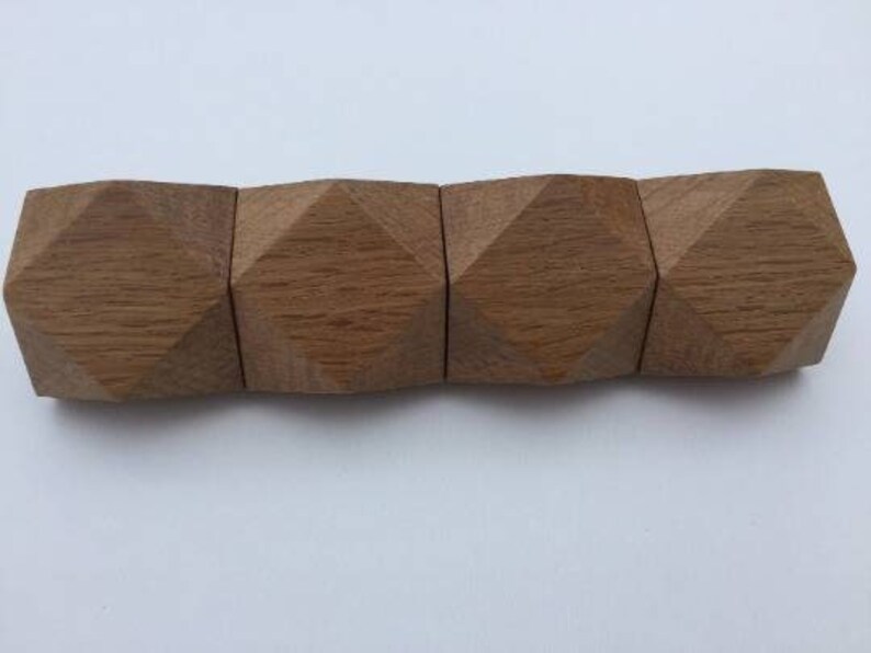 以下が含まれることがあります： ダイヤモンド型の面を持つ木製の幾何学的な形が5つセットになっています。 形はつながっていて、長い長方形のピースを形成しています。 木材は薄い茶色です。