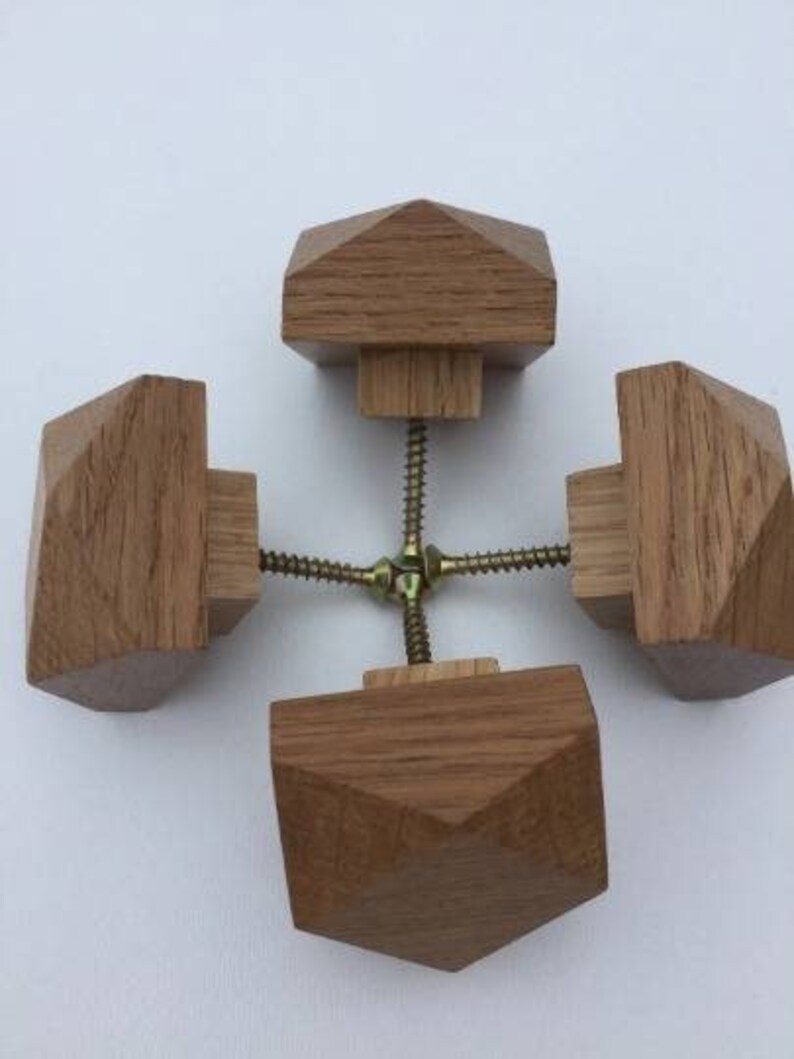 以下が含まれることがあります： 幾何学模様のついた木製のノブが4つ。ノブは金属製のネジでつながっています。ノブは薄い茶色です。