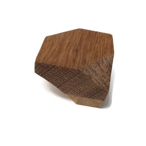 Puede incluir: Un pomo de armario de madera con forma geom&eacute;trica, de color marr&oacute;n claro y superficie texturizada.