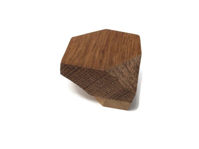 Puede incluir: Un pomo de armario de madera con forma geom&eacute;trica, de color marr&oacute;n claro y superficie texturizada.