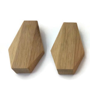 Può includere: Due pomelli in legno per mobili dalla forma geometrica a diamante. I pomelli sono realizzati in legno chiaro, con venature visibili. Sono progettati per mobili e decorazioni per la casa.