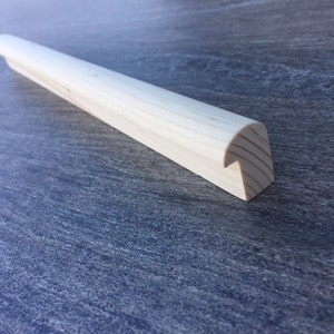 Può includere: Un corrimano in legno con un'estremità arrotondata. Il corrimano è in legno chiaro e ha una finitura liscia.