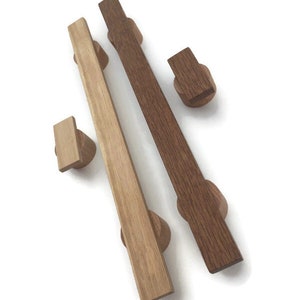 May include: Two wooden cabinet pulls and two matching knobs. One pull is light-colored, the other is dark brown. The knobs are small and rectangular. The pulls are approximately 8 inches long.