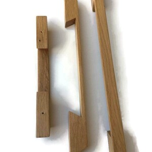 May include: Three wooden cabinet door pulls in various sizes. The pulls are made of natural wood and have a simple, modern design.