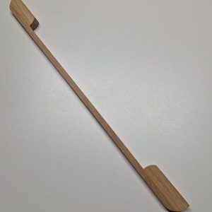 May include: A wooden cabinet door handle with a simple, minimalist design. The handle is made of light brown wood and has a slightly curved shape.