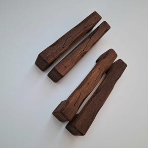 Op de afbeelding: Drie paar houten eetstokjes, elk paar gestapeld op elkaar. De eetstokjes zijn donkerbruin en hebben een natuurlijke houtnerf.