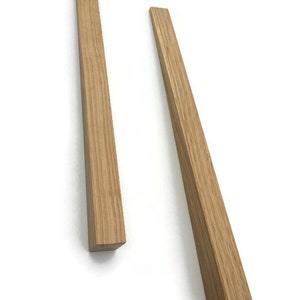 Könnte beinhalten: Zwei Holzstift, einer länger als der andere, werden vor einem weißen Hintergrund gezeigt. Die Stifte sind aus hellbraunem Holz mit natürlicher Maserung.