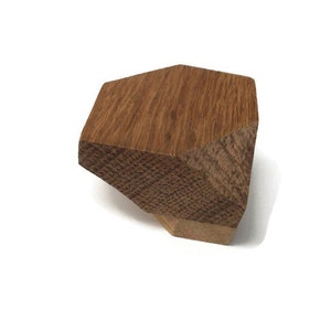 Puede incluir: Un pomo de madera con forma geom&eacute;trica, de color marr&oacute;n claro y superficie texturizada.