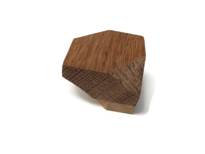 Puede incluir: Un pomo de madera con forma geom&eacute;trica, de color marr&oacute;n claro y superficie texturizada.