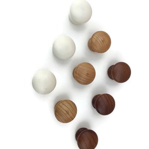May include: Nine wooden knobs in three colors: white, light brown, and dark brown. The knobs are arranged in a diamond shape on a white background.