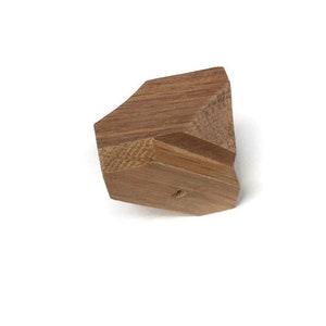 Puede incluir: Una forma geom&eacute;trica de madera de color marr&oacute;n claro. La forma tiene un agujero en el centro.