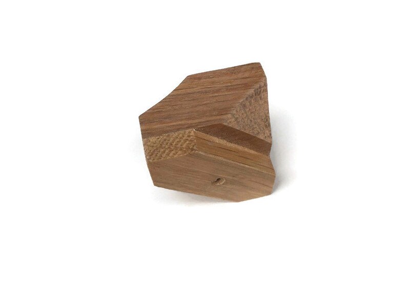 Puede incluir: Una forma geom&eacute;trica de madera de color marr&oacute;n claro. La forma tiene un agujero en el centro.