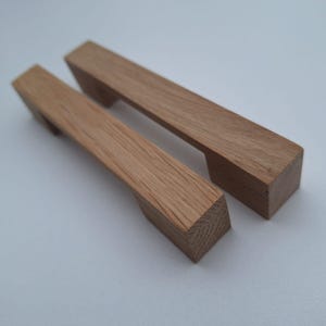 May include: Two wooden cabinet pulls with a rectangular shape and a smooth, natural finish.
