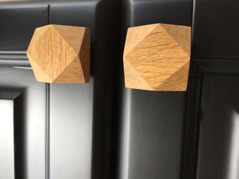 以下が含まれることがあります： 幾何学模様のウッドキャビネットノブ2個。ノブは薄い茶色で、ダイヤモンド型をしています。