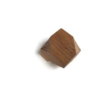 Puede incluir: Un pomo geom&eacute;trico de madera con forma hexagonal y color marr&oacute;n claro.