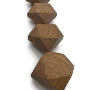 以下が含まれることがあります： ダイヤモンドの形をした薄い茶色の木製のノブが4つ、一列に並んでいます。