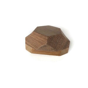 Puede incluir: Un pomo geom&eacute;trico de madera con un acabado marr&oacute;n. El pomo tiene un dise&ntilde;o facetado y est&aacute; formado como una piedra preciosa.