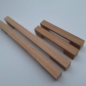 Könnte beinhalten: Drei Holzknaufgriffe in verschiedenen Größen. Die Griffe sind aus hellbraunem Holz mit natürlicher Maserung.