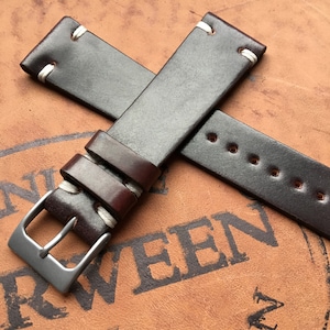 May include: Two brown leather watch straps with white stitching. One strap has a metal buckle.