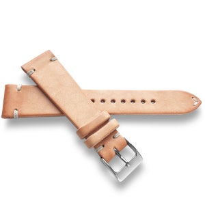 May include: A light brown leather watch strap with white stitching and a silver buckle.
