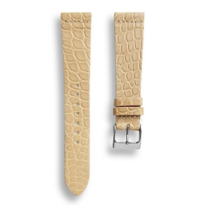 May include: A light beige alligator leather watch strap with a silver buckle.