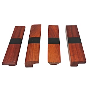 May include: Four wooden cabinet pulls with a black inlay. The pulls have different shapes and sizes.