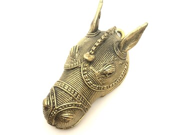 Può includere: Una scultura in metallo dorato a forma di testa di cavallo con dettagli intricati. La scultura è realizzata in un materiale testurizzato e ha un aspetto realistico.